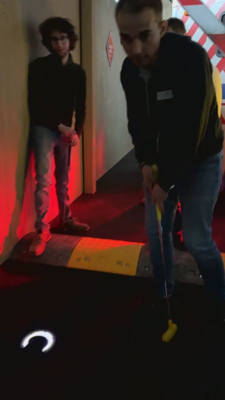 Un joueur s'apprête à frapper sur un trou lumineux de Prison Golf
