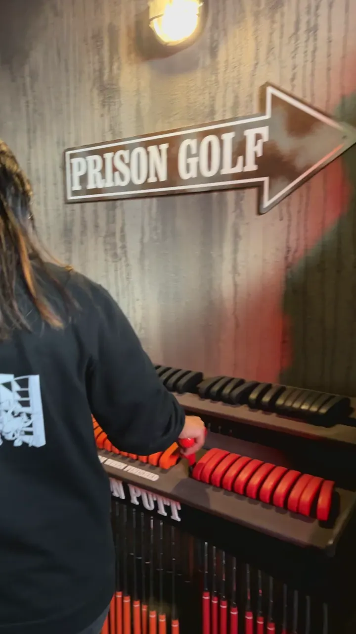 Une joueuse choisit son club au départ du parcours de Prison Golf