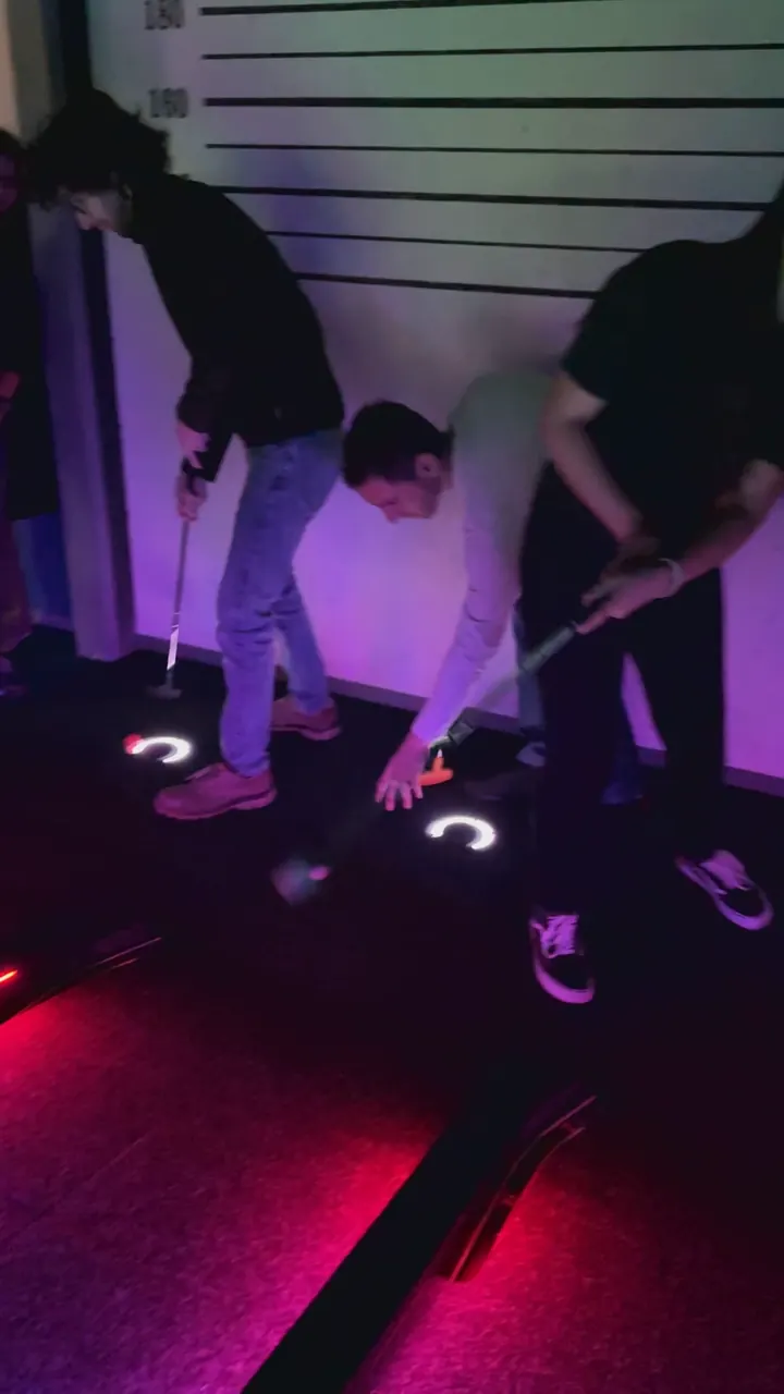 Deux joueurs penchés sur un trou lumineux, clubs en main
