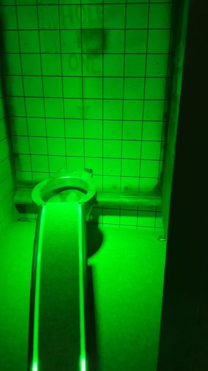 Une rampe éclairée en vert dans un couloir carrelé